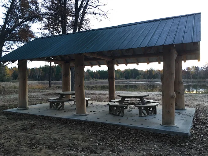 Wooden picnic shelter by lake in autumn.